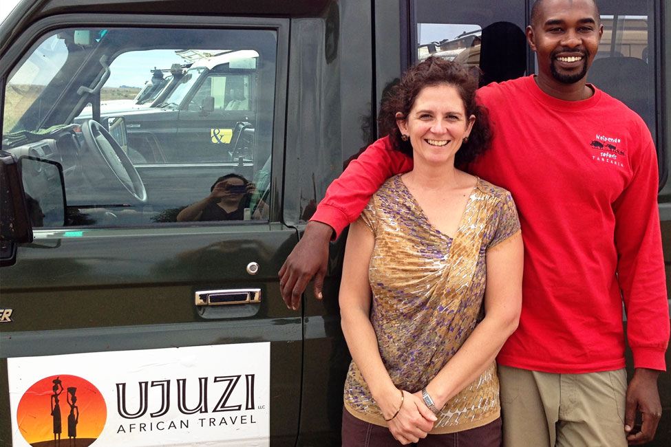 ujuzi owner anne medeiros and guide stand next to an Ujuzi safari vehicle