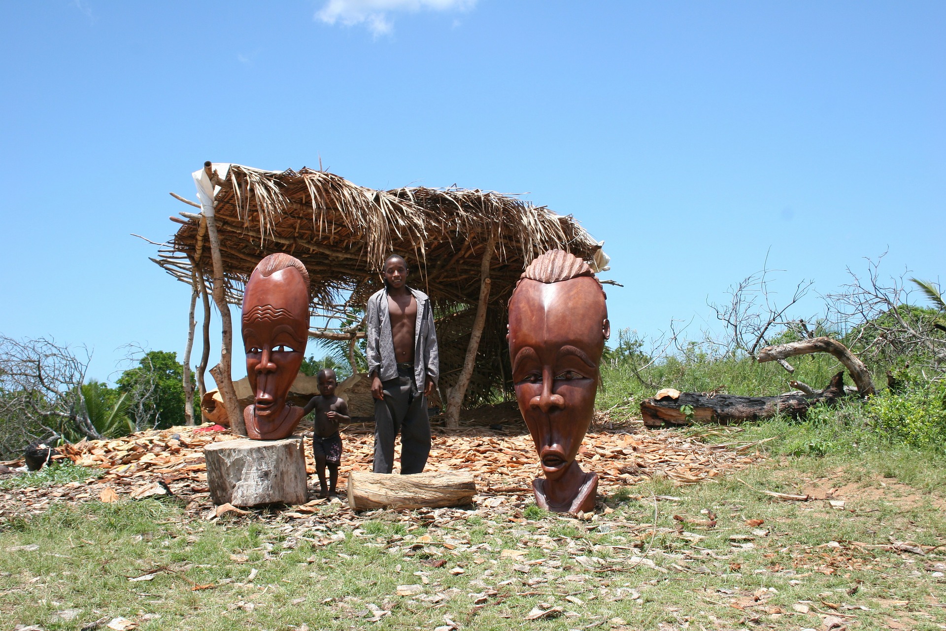 person stands between two large wooden sculptures in Mozambique
