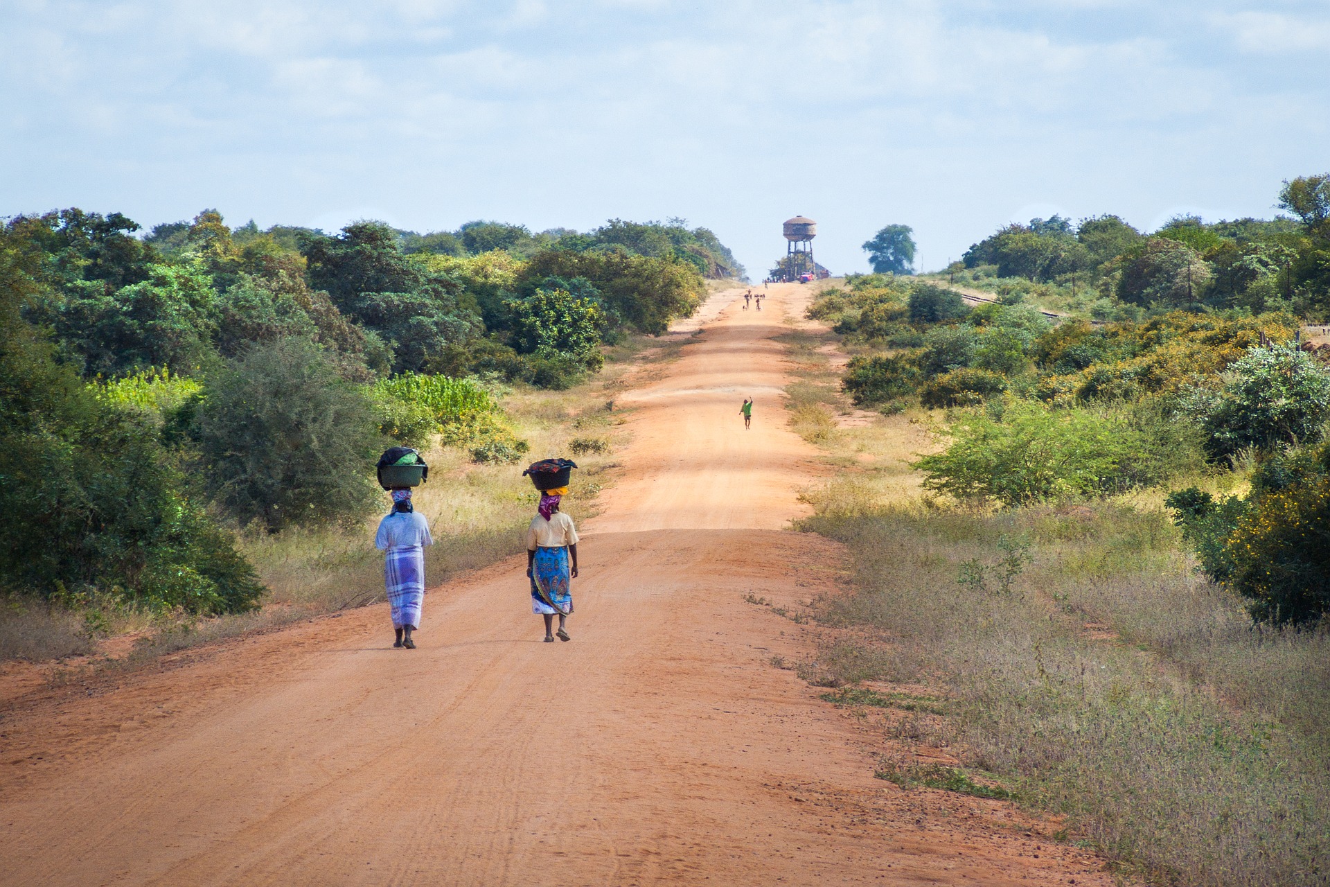 Women carry baskets on their heads as they walk down dirt road in Mozambique Africa