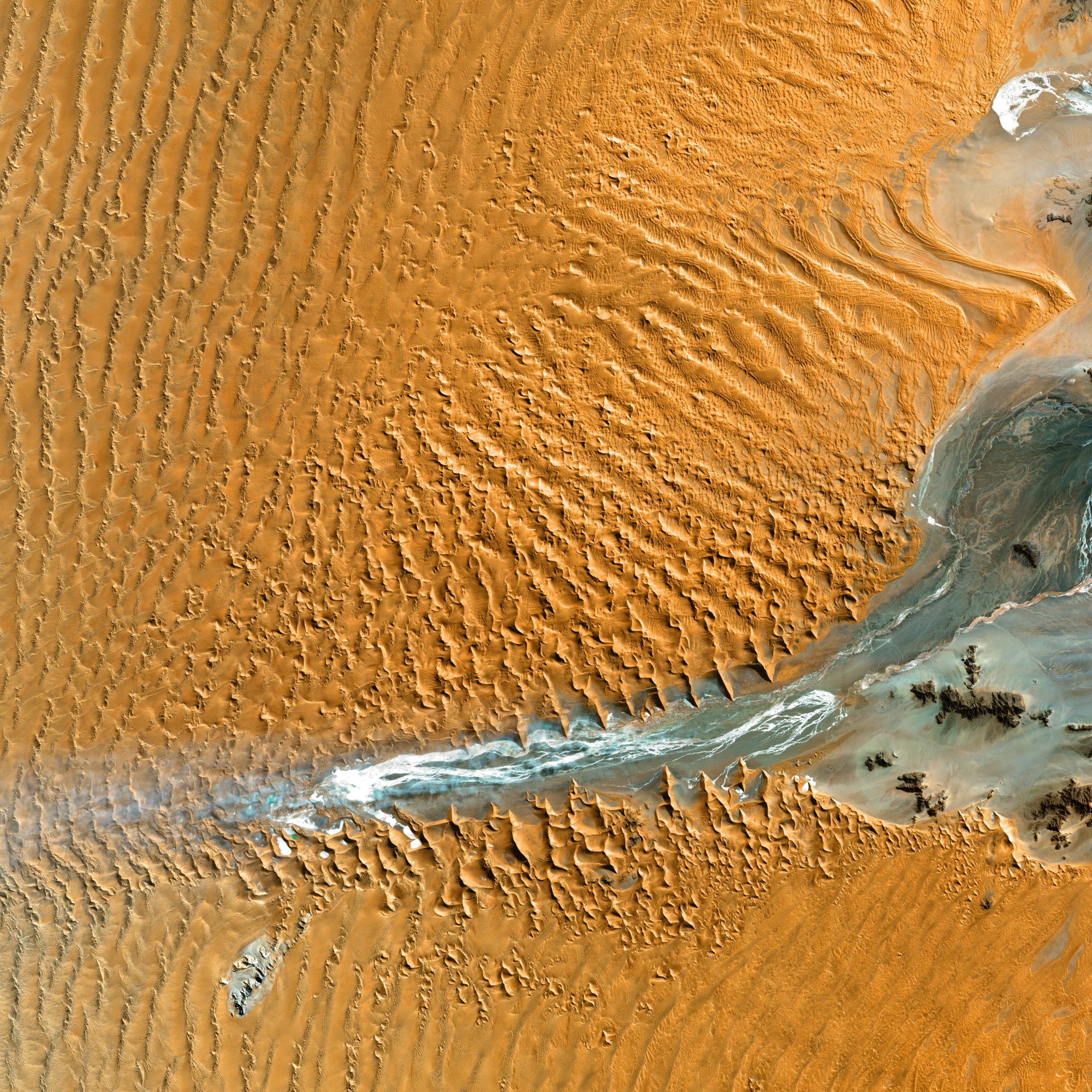 Aerial view of seasonal water body in an orange sand desert in Namibia