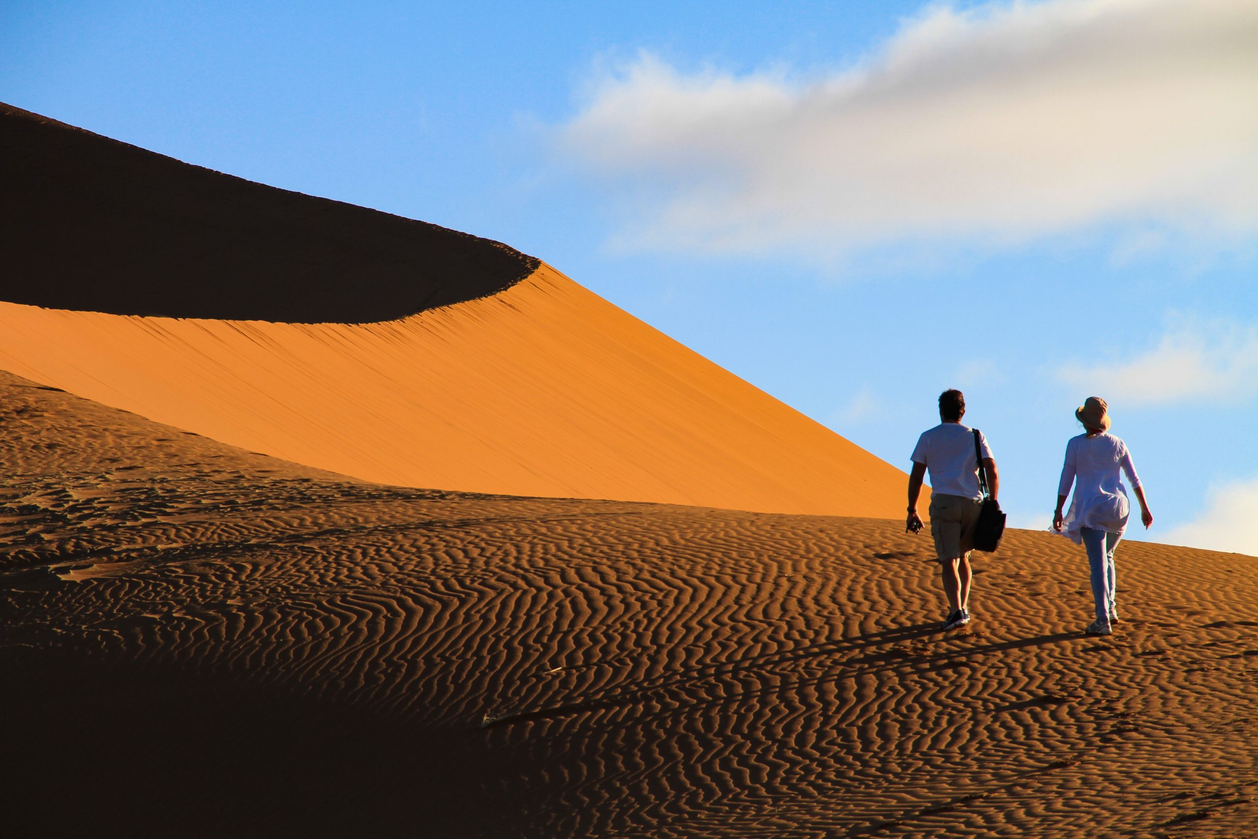 two people walk along a red sand dune in Sossusvlei Namibia