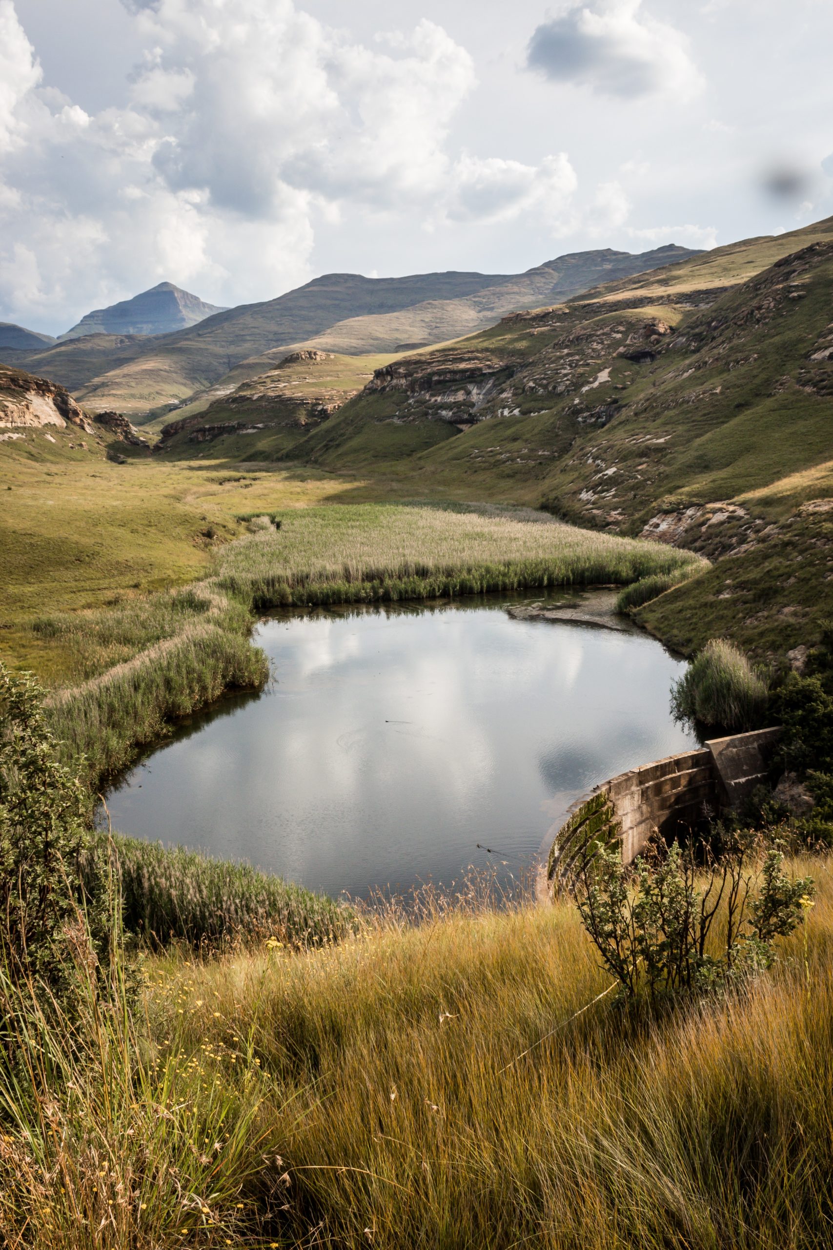 small lake surrounded by hills and reflecting cloudy skies in South Africa
