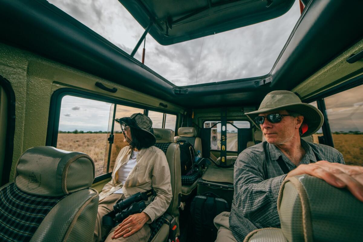 People on a safari in tanzania sit in a safari vehicle and look out the window