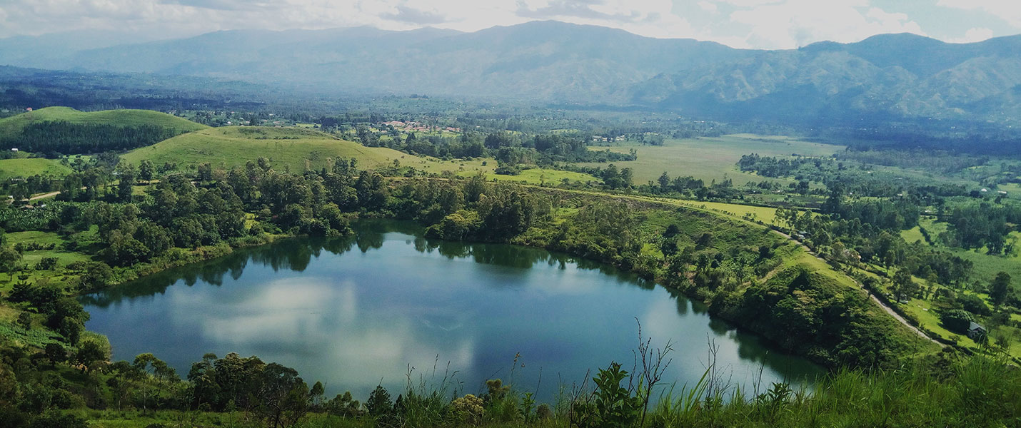 aerial view of a pond amid lush rolling hills in Uganda