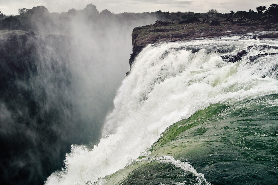 River water forms white caps as it rushes over the edge of Victoria Falls.