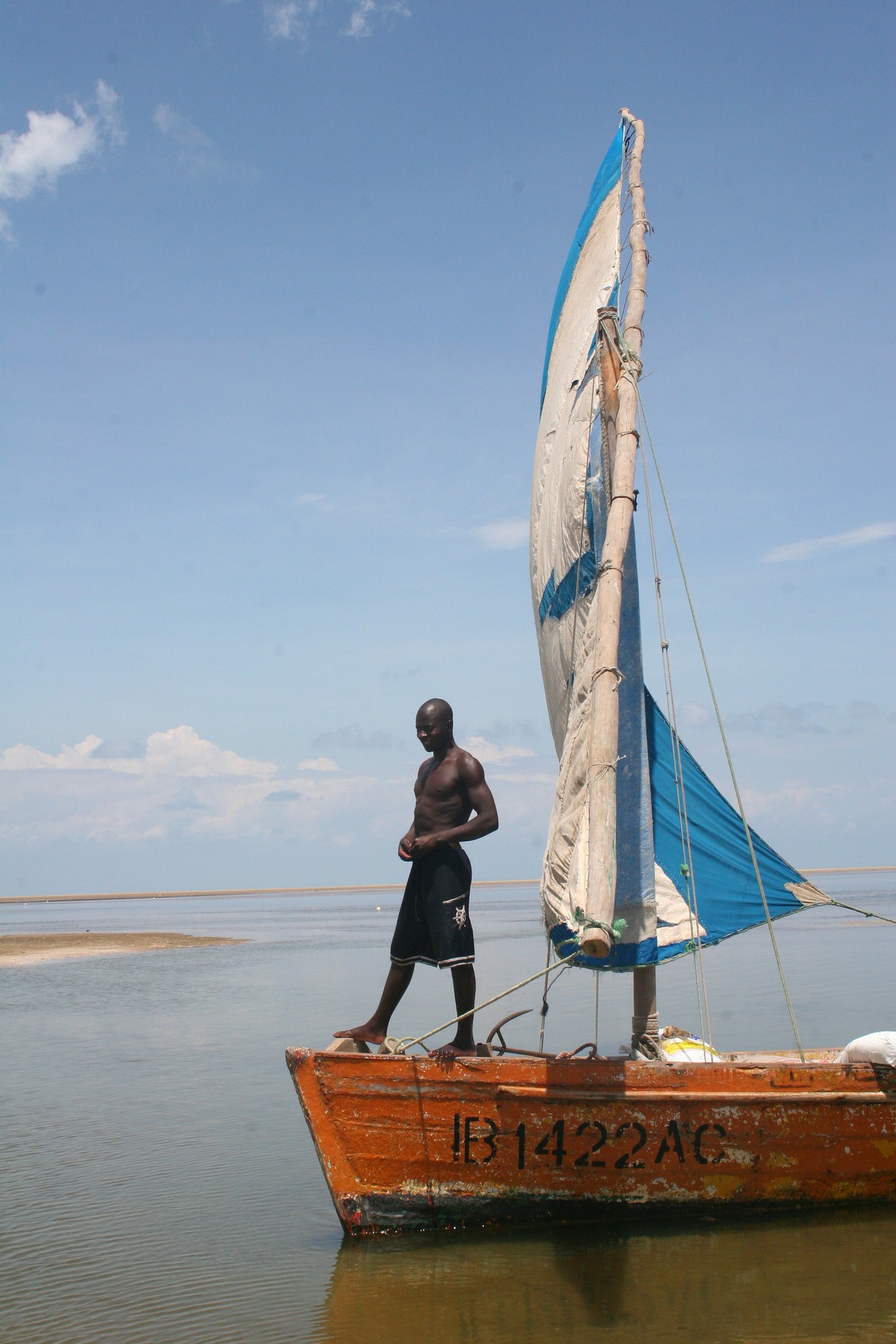 Person stands on the bow of a small sailboat off the coast of Mozambique