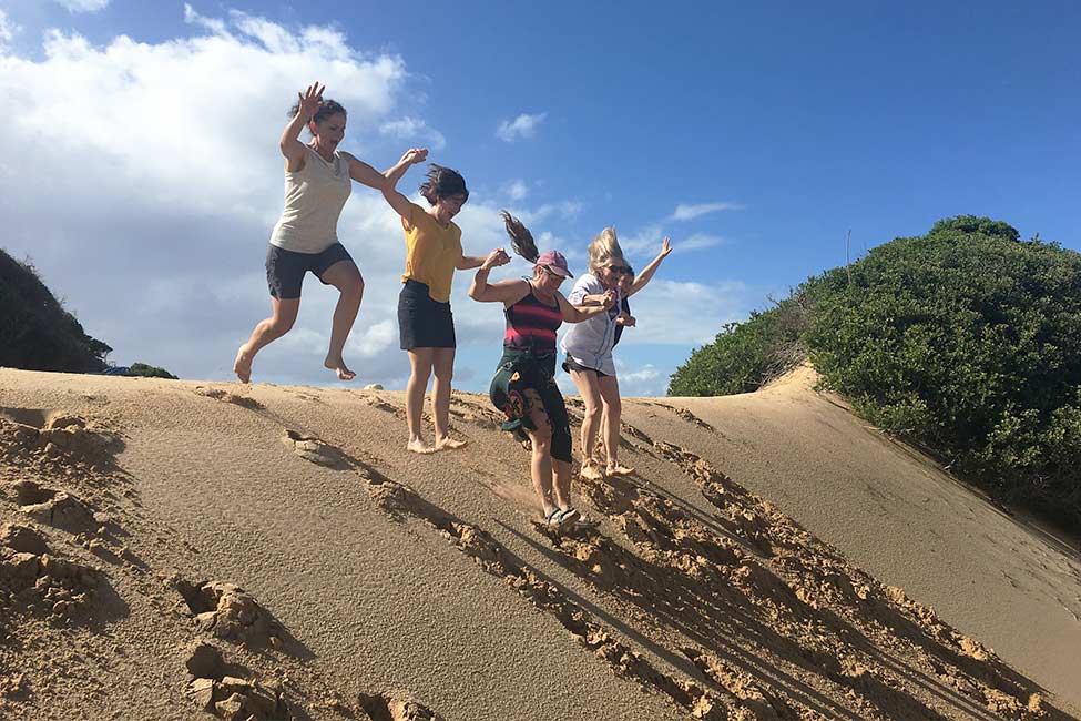 people jumping on a sand dune in Machangulo Sand Dunes, Mozambique