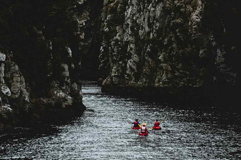 3 kayakers paddle down a river in South Africa