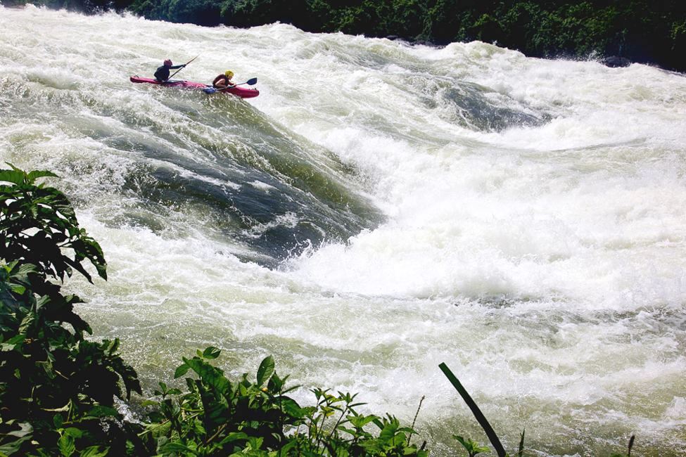 Two people on a kayak ride turbulent waves of the nile river near jinja