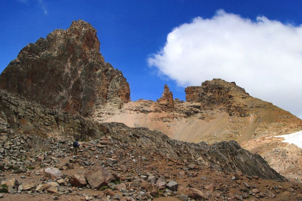 Reddish-brown rocky peak with patch of snow on Mount Kenya
