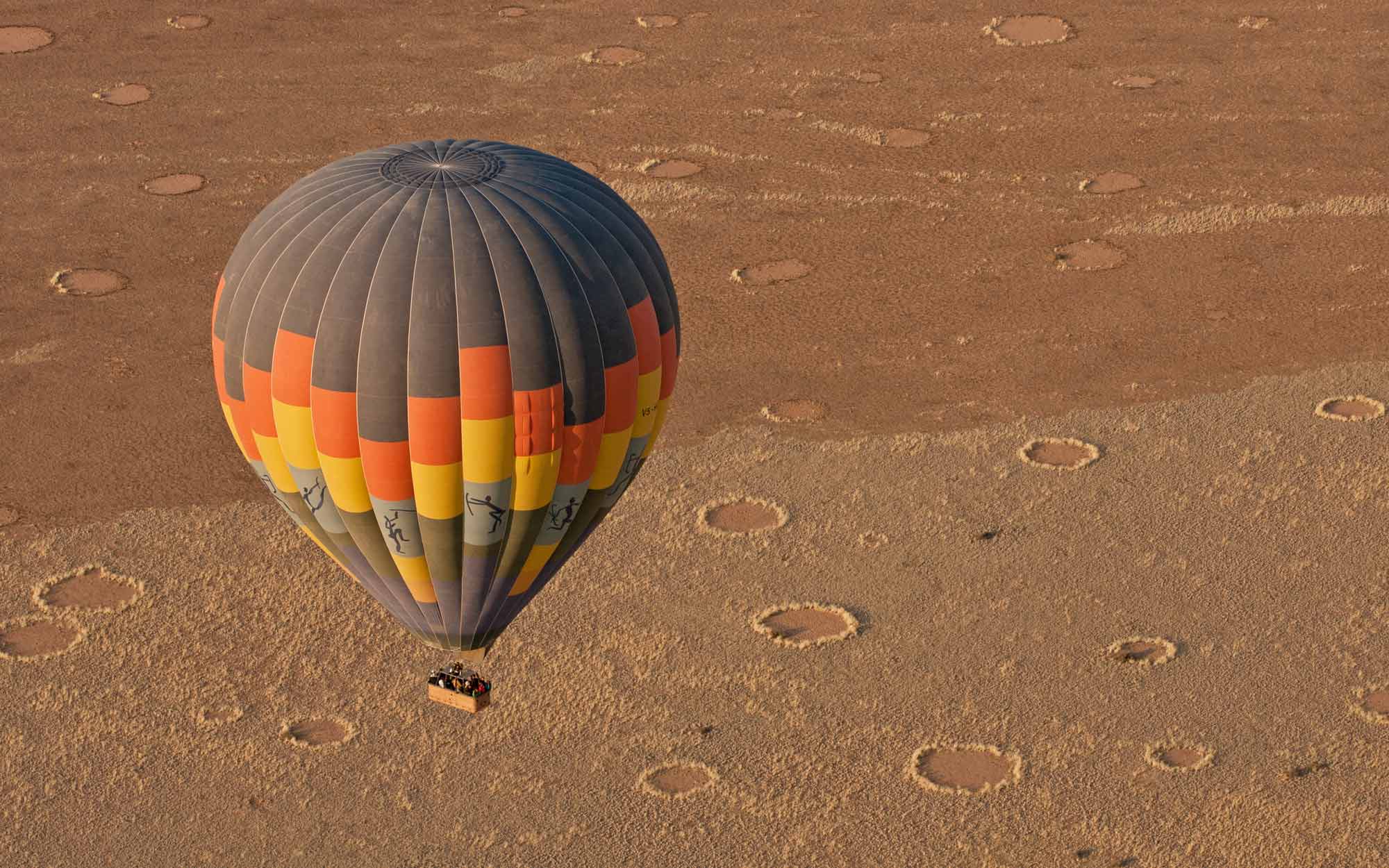 a hot air balloon floats over dessert in Namibia Africa