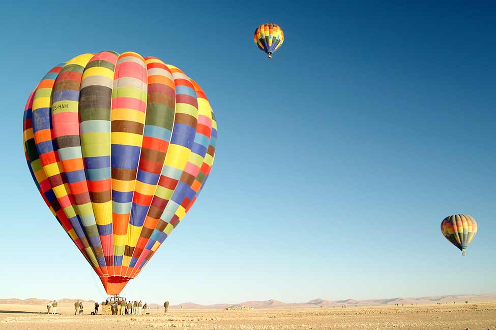 Namibia-Sossusvlei-Ground-Hot-Air-Balloon-Sky-Ujuzi-975×650 three colorful hot air balloons launch in Sossuvlei dessert Namibia Africa
