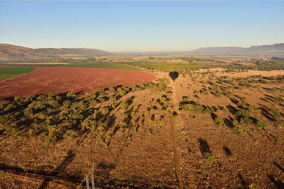 a hot air balloon floats above bucolic land in South Africa