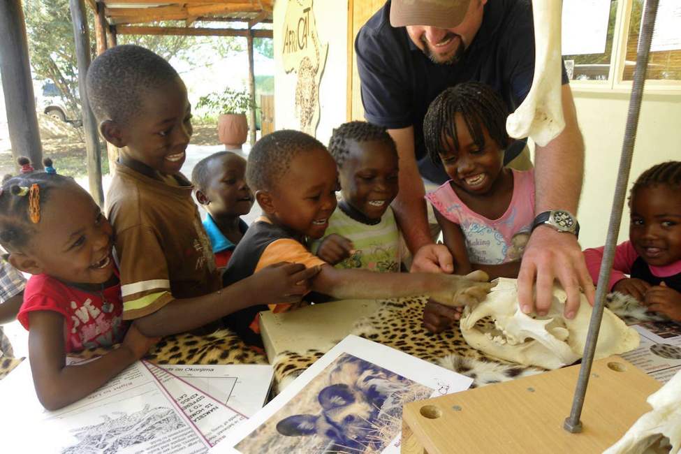 Smiling children look at educational materials about large cats at AfriCat wildlife rehabilitation program at okonjima nature reserve