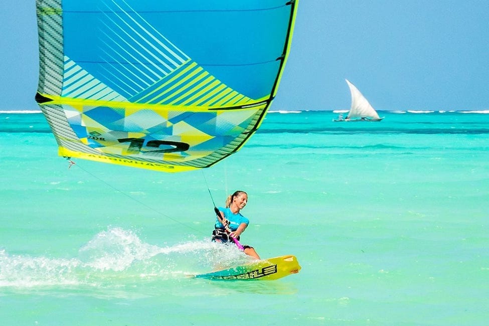 person smiles while kitesurfing on clear blue water in Zanzibar