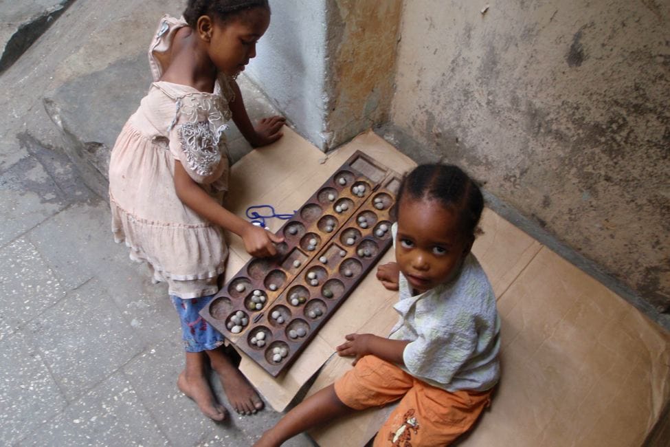 two children play a traditional board game called bao in Stone Town Zanzibar