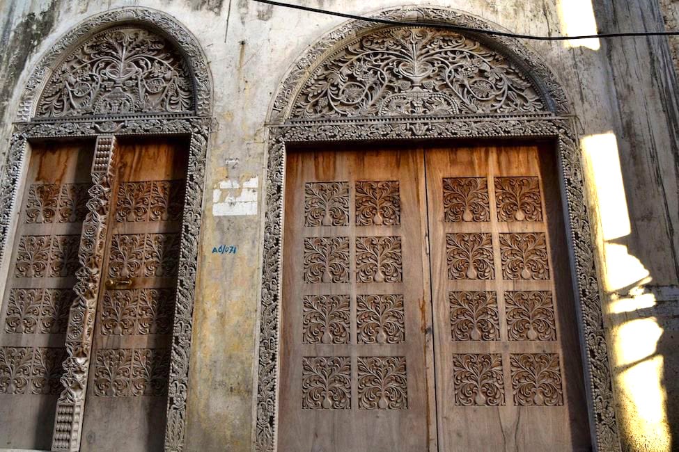 stone building with carved wooden doors and intricate stone carving above the doors