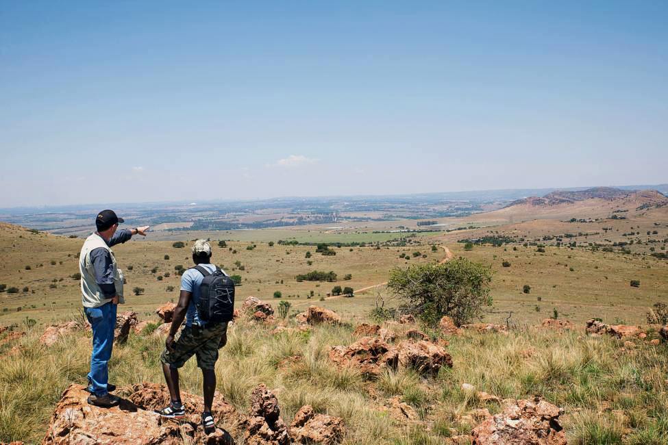 two people stand on a rock overlooking the plains around the cradle of humankind in South Africa
