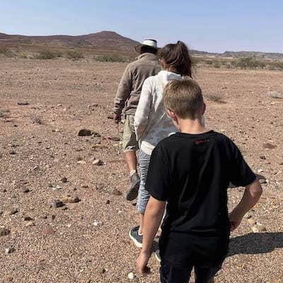 Namibian guide and two children walk in Namibian desert