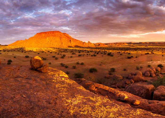 colorful sunset image of reddish rock outcrop in Damaraland Namibia with dramatic purplish cloudy sky